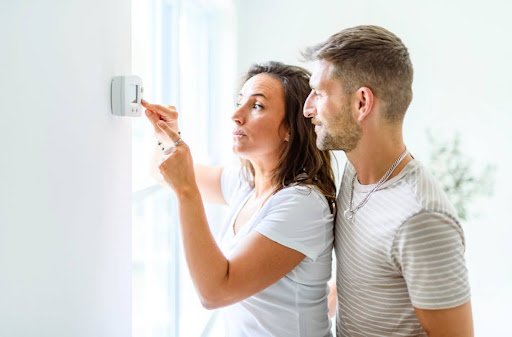 Couple checking thermostat.