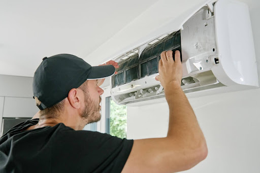 Falls Heating & Cooling technician checking indoor AC unit.